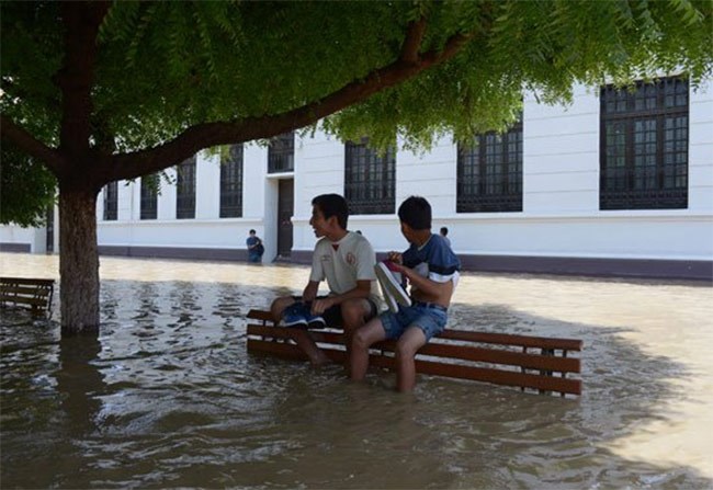  مواطنون يحملون أمتعتهم فى محاولة لعبور مياه الفيضان